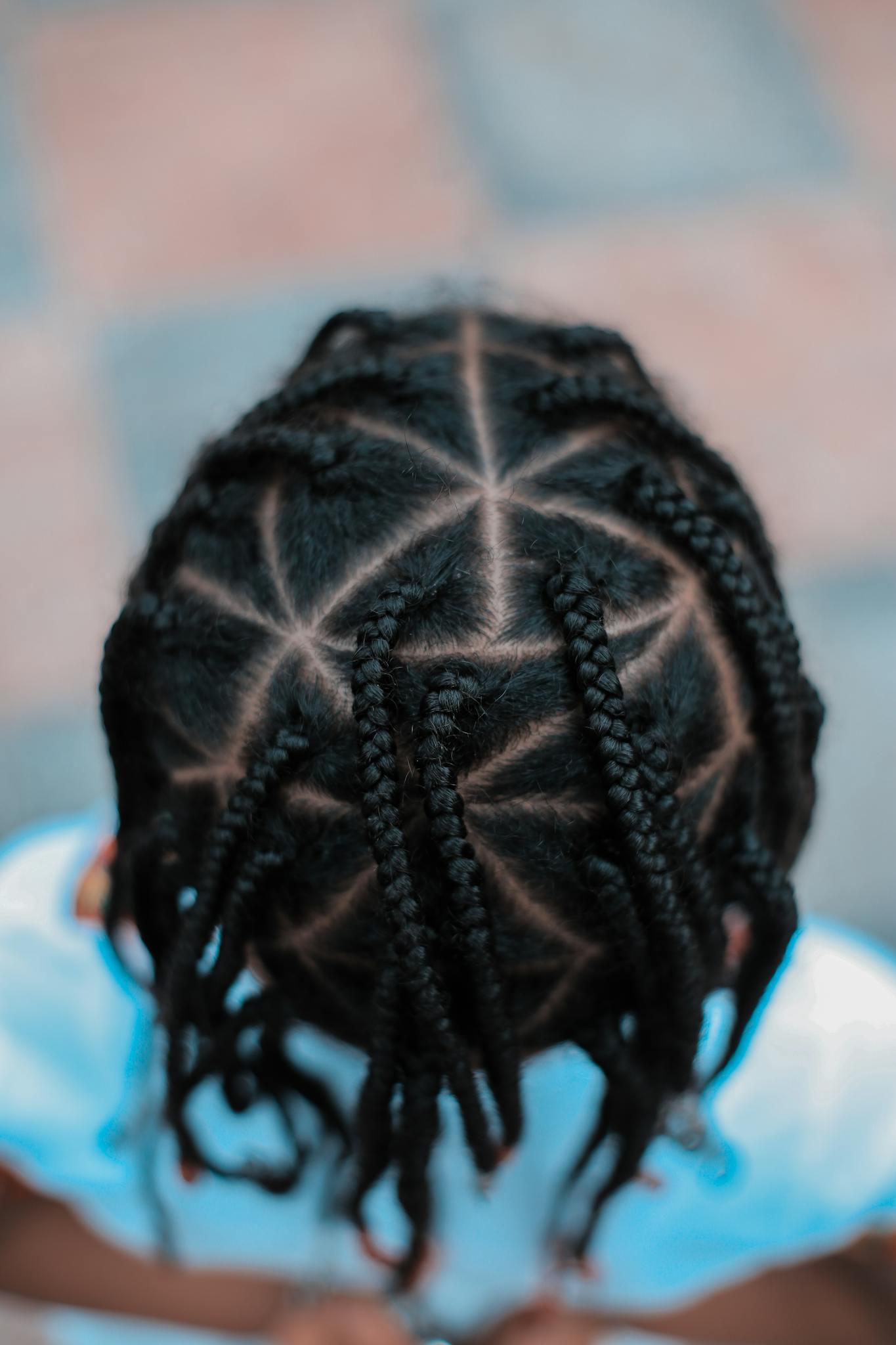 Close-up top view of intricate braided hairstyle on a child, showcasing a unique pattern.