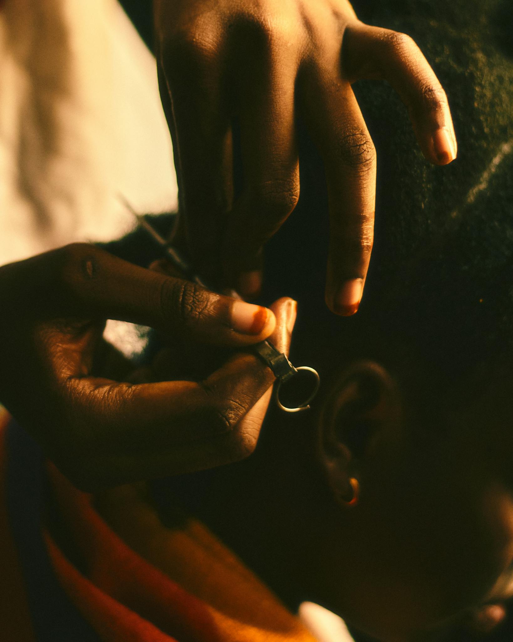 Detailed view of hands braiding hair, showcasing intricate styling in warm lighting tones.